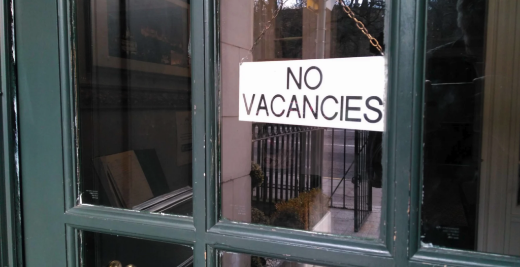 Photo of a door with a no vacancy sign.