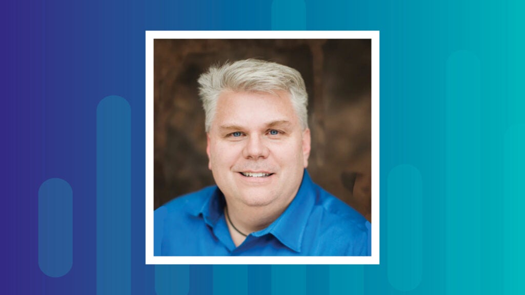 Headshot of Rob McCann, CEO of Catholic Charities Eastern Washington. He is wearing a blue button down shirt and smiling.