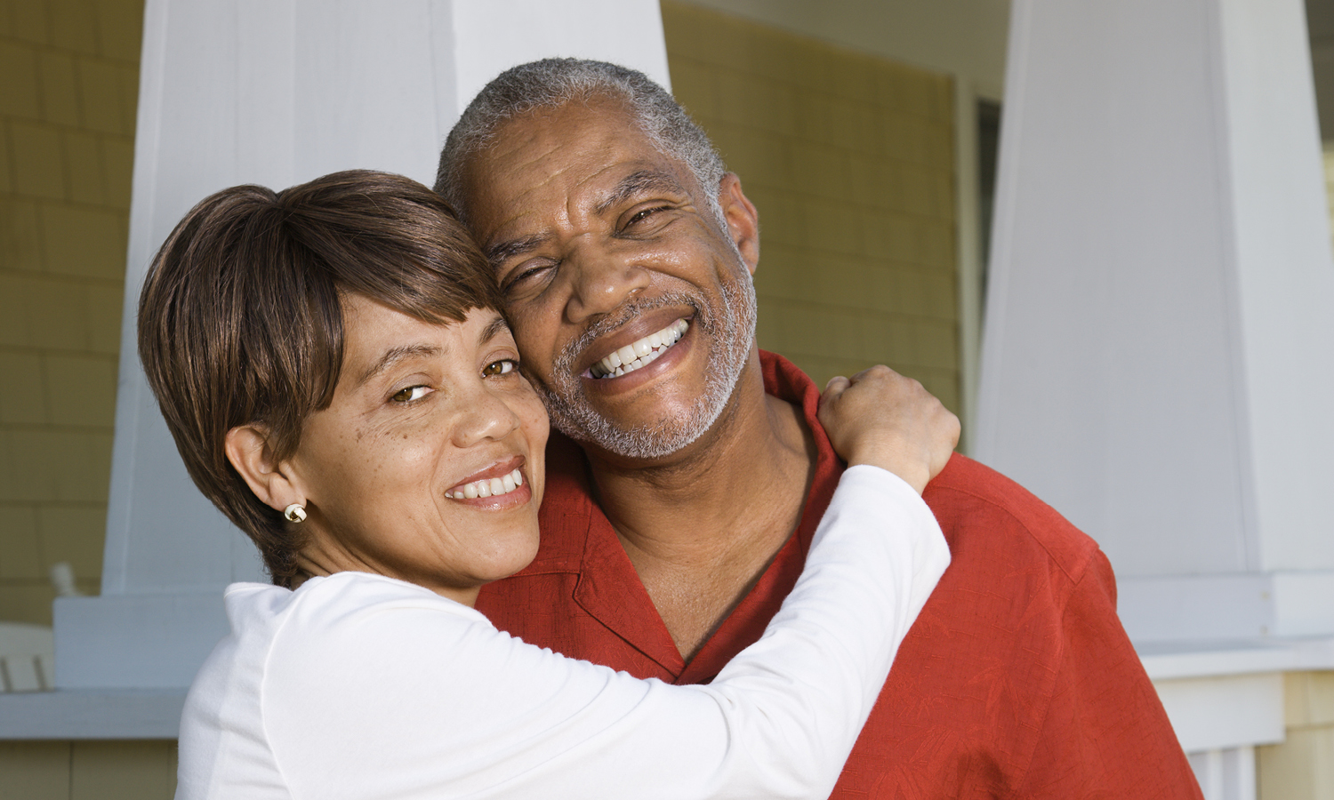 A smiling older couple hug and look happy to be together in a nice home. 