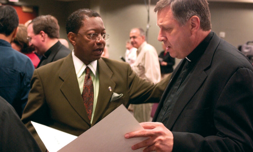 Two men speak with each other at a conference. 