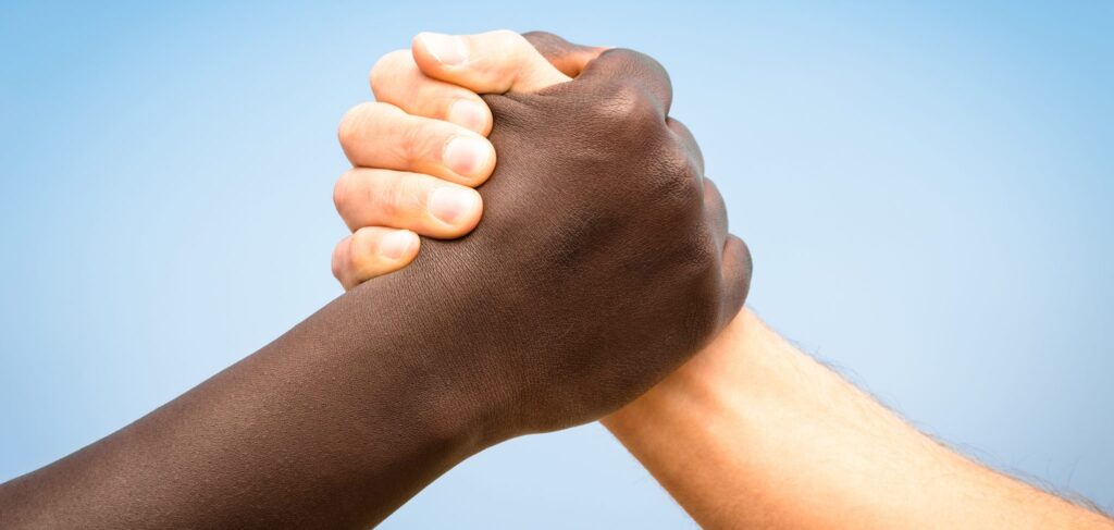 Two hands are clasped in friendship -- one white, one Black.