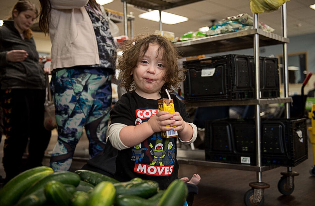 Little kid at a food pantry drinking chocolate milk and smiling