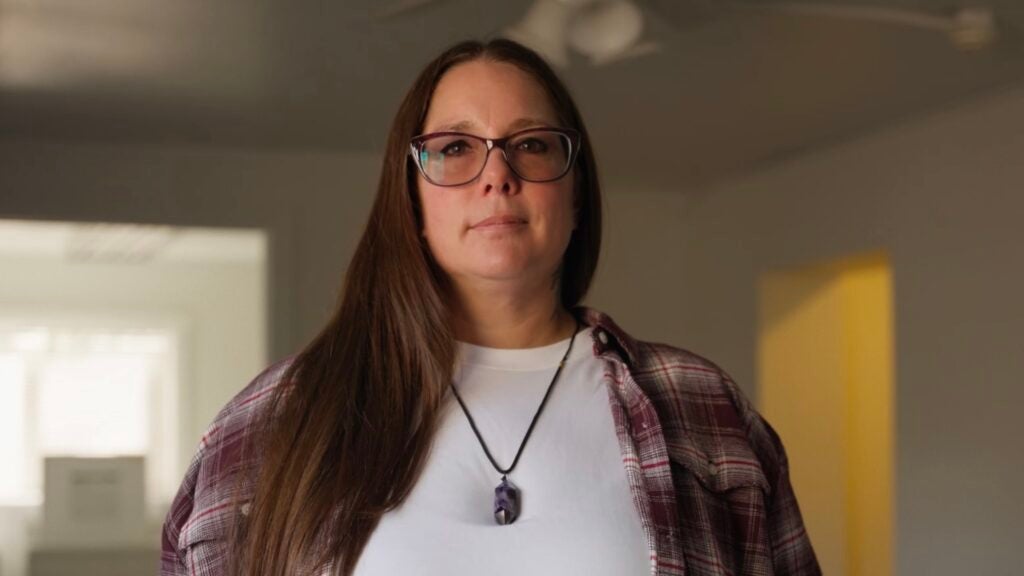A client of Catholic Charities Community Services (Arizona) is pictured in a white t-shirt and flannel shirt.
